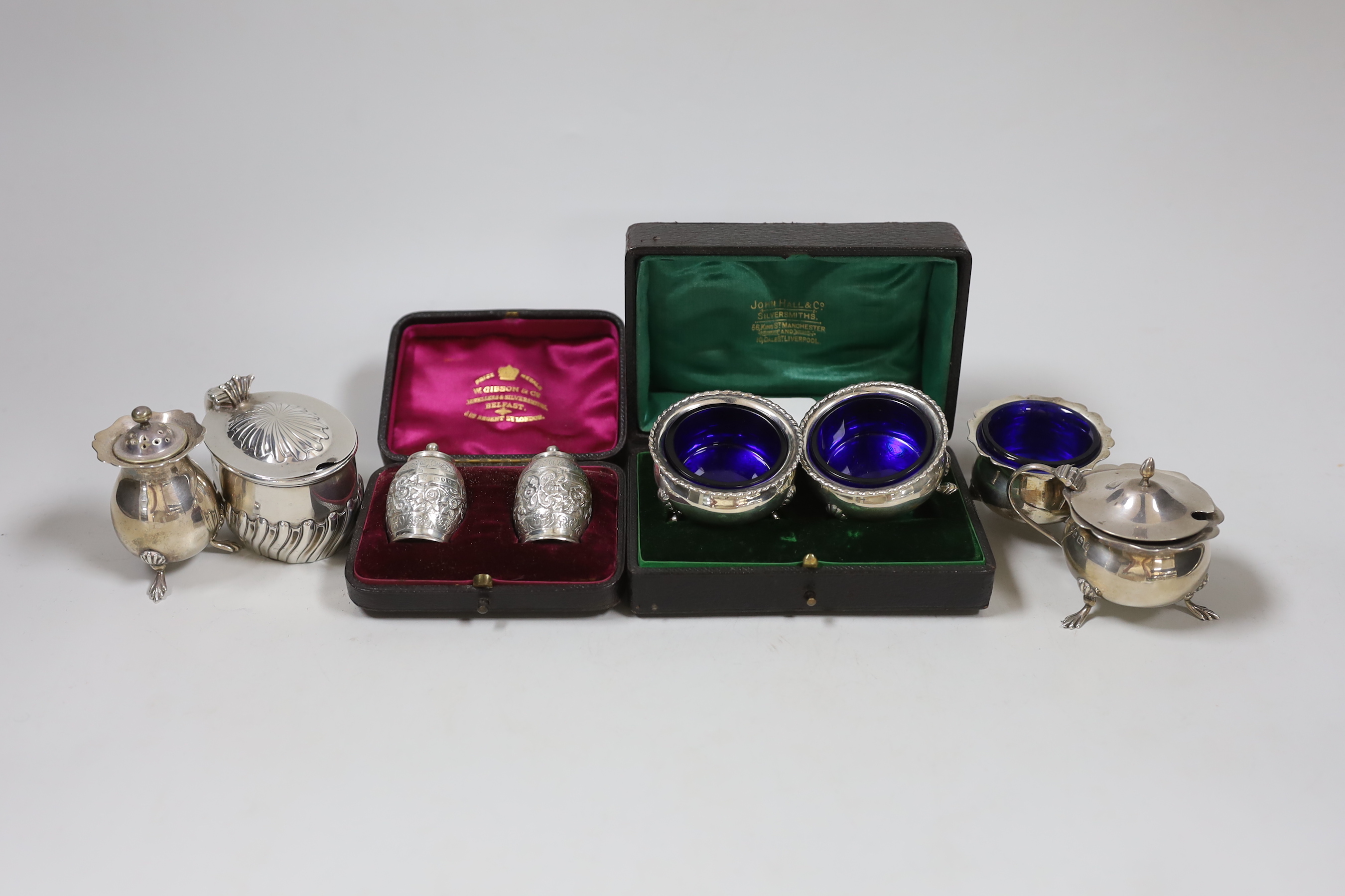 Two cased pairs of silver condiments including chased pepperettes, 45mm and four other silver condiments.